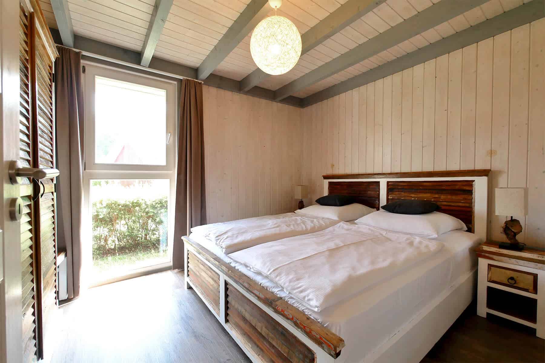 Ferienhaus Seeperle XL am Scharmützelsee. Schlafzimmer im Erdgeschoss mit großem Doppelbett und bodentiefen Fenster.