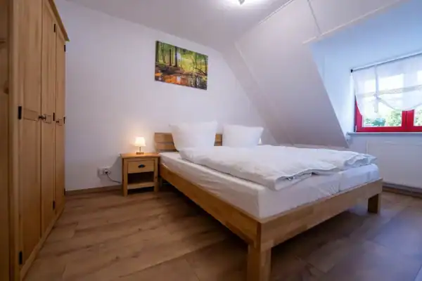 A bedroom with a bed and wood-look floor. Ein Schlafzimmer mit einem Bett und Boden in Holzoptik.